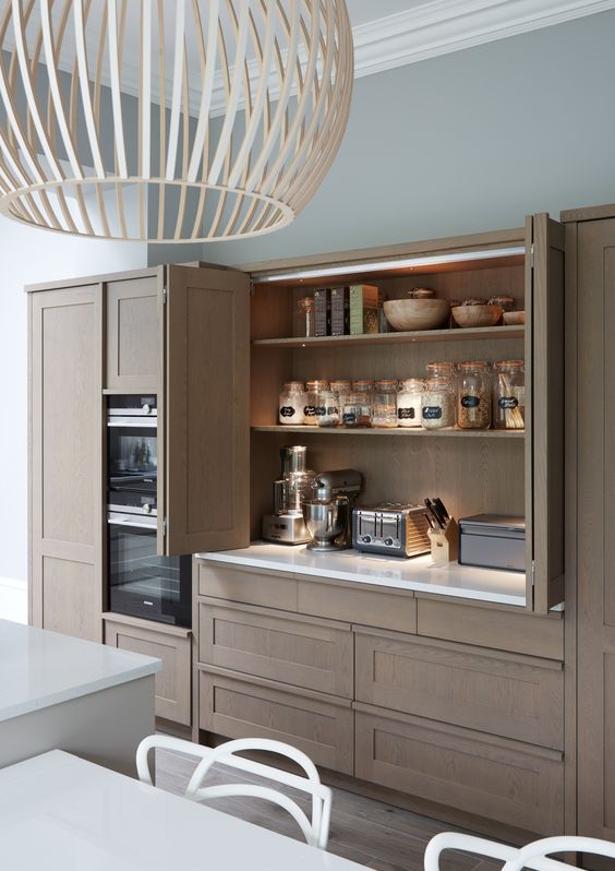 A beautiful and sleek stained wooden cabinet with small appliances hidden inside it, with built-in lights and bi-fold doors for comfortable using.