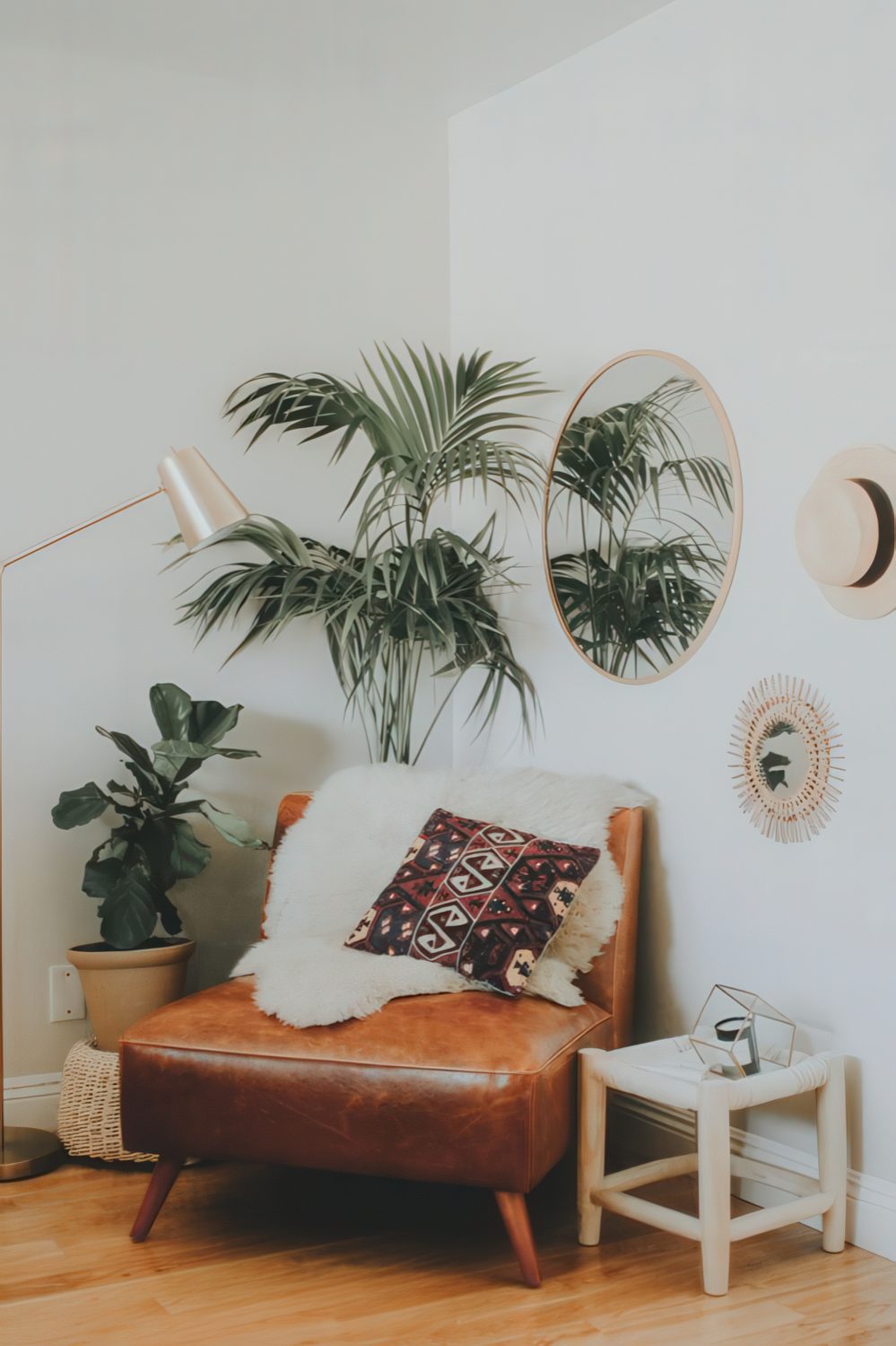 A boho nook with a leather chair, some potted greenery, a mirror and a lamp makes up a cozy reading space.