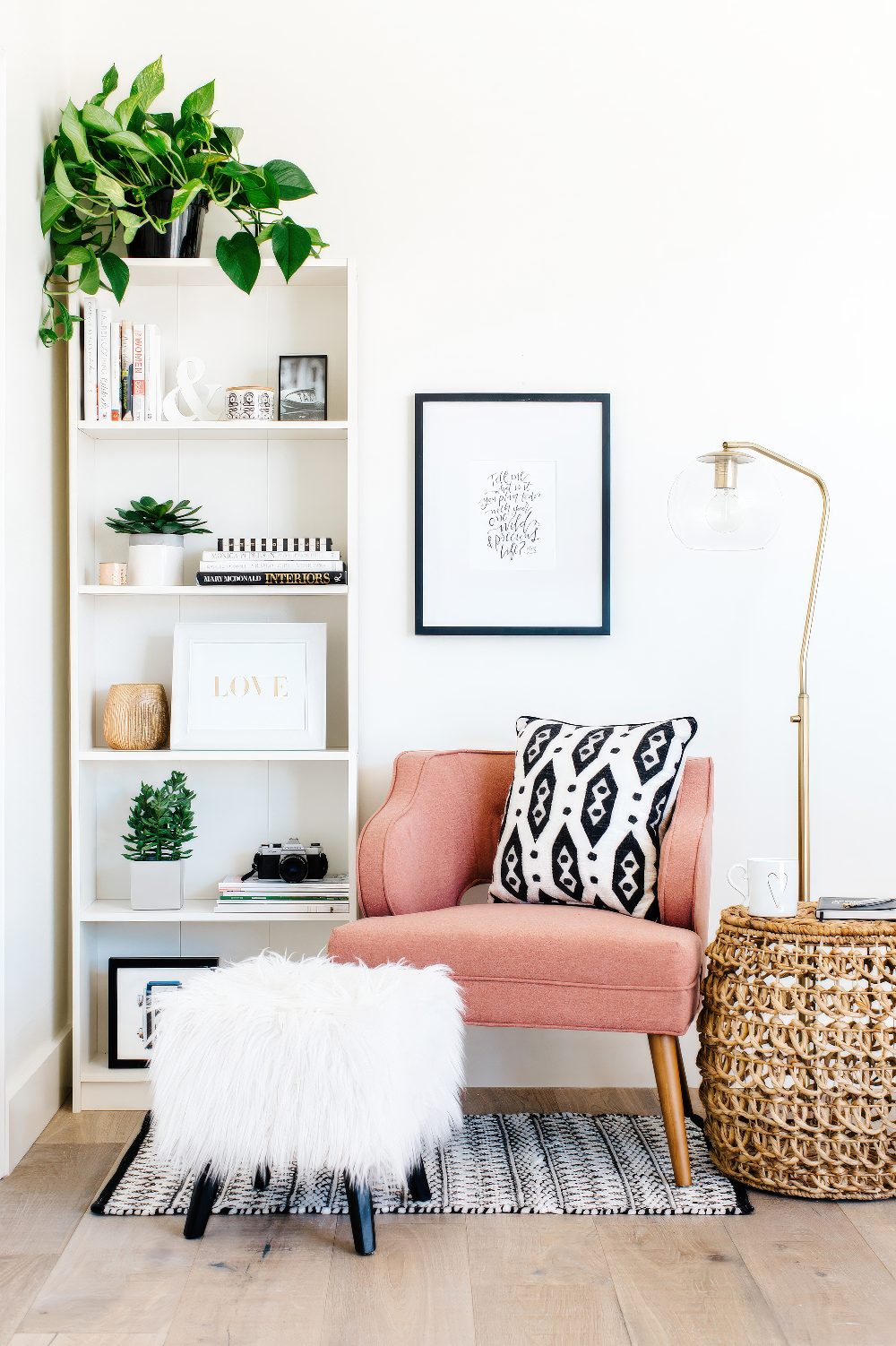 A cozy corner with a pink armchair, a floor lamp and some poufs is an ideal reading nook and is very inviting.