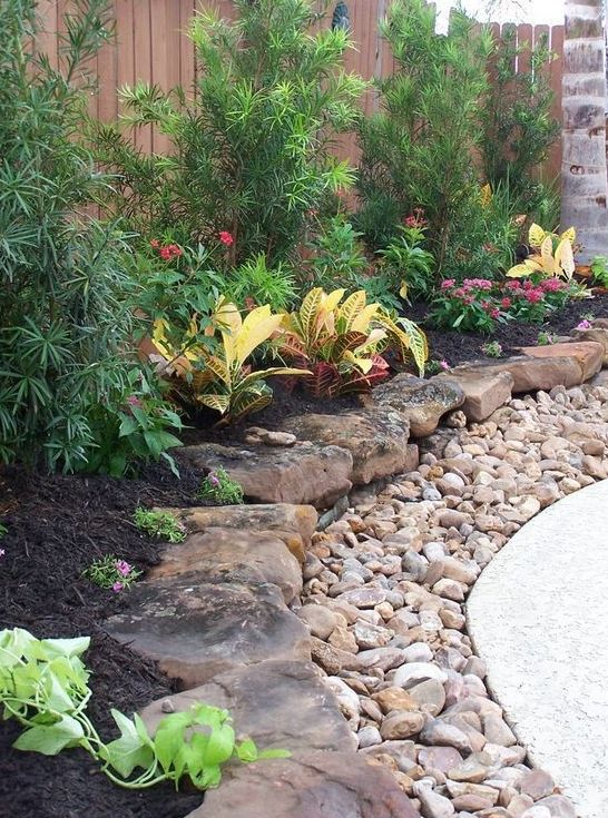 A large pebble and rough rock garden border brings much texture and a rough touch to the elegant outdoor space.