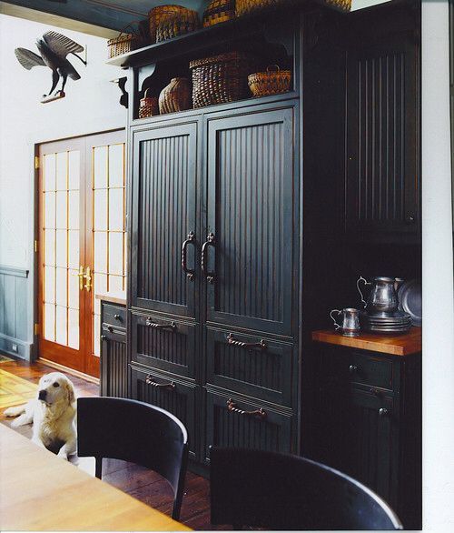A fridge and freezer integrated into vintage kitchen decor featuring the same doors and handles.