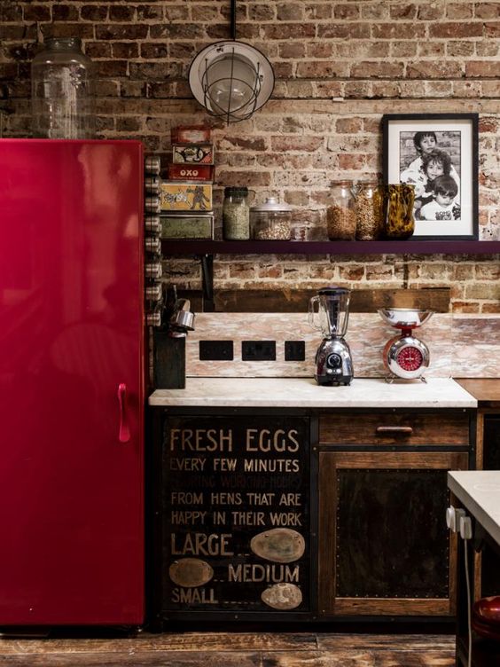 An industrial kitchen with a shiny red fridge to make a statement with color.