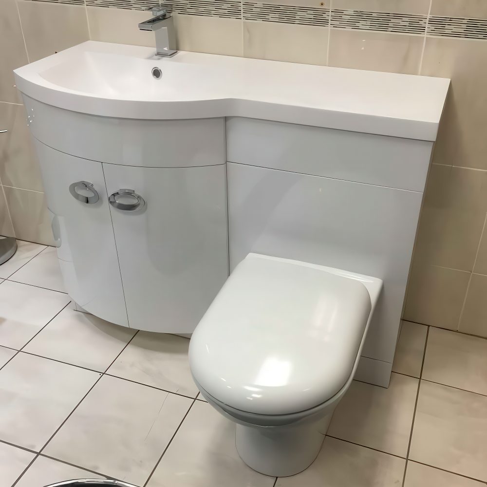 Curvy sink with a countertop and a toilet.