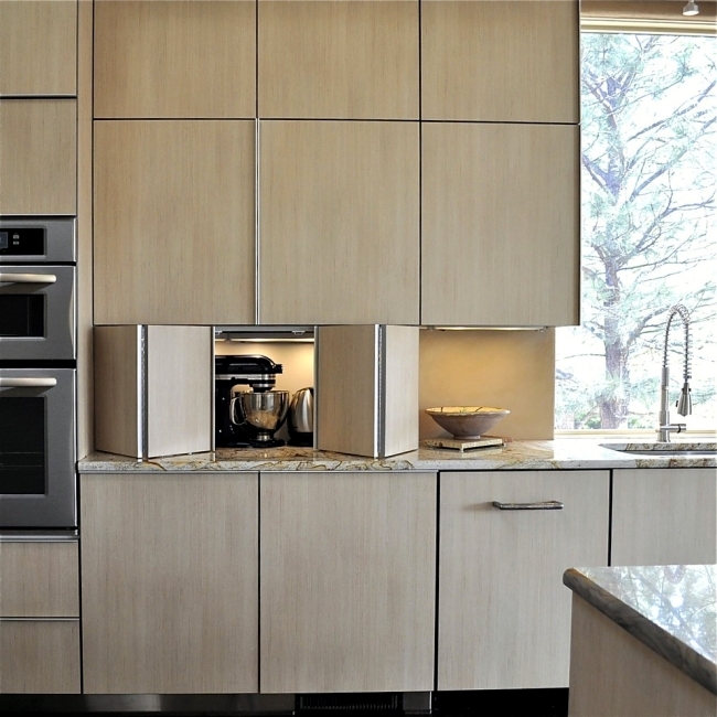 A sleek contemporary kitchen with lower cabinets featuring bi-fold doors and lights inside to hide the appliances.