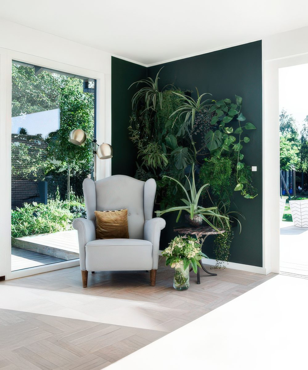 An awkward nook with a living wall, a comfy chair and a table, lots of greenery, it looks very inspiring and refreshing.
