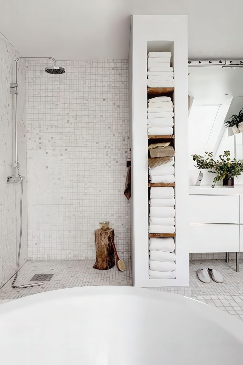 A built-in shelving unit that doubles as a shower space divider and holds all the towels is a smart solution.