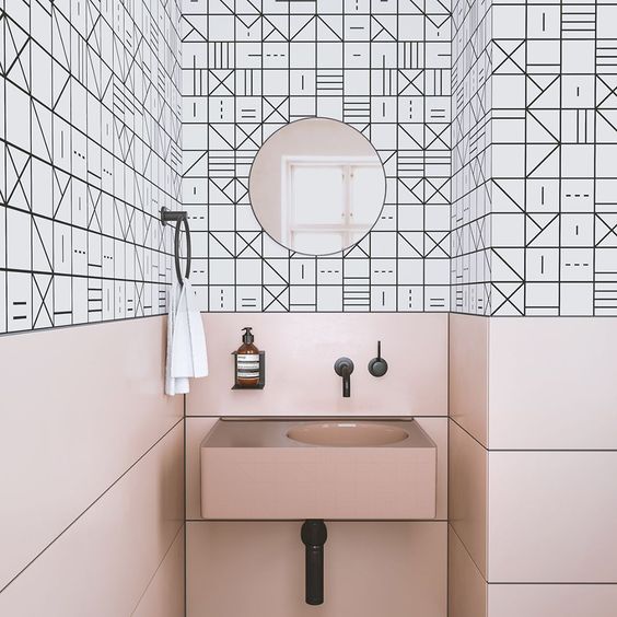 Pink panels and a sink contrast the geometric black and white tiles and create a unique space.