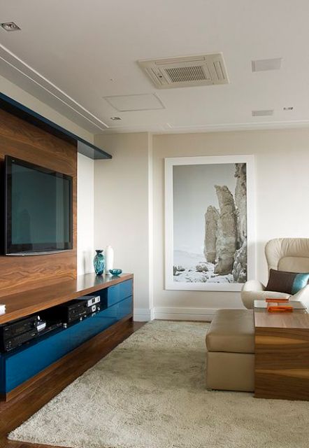 A modern living room done in neutrals, with a wall-mounted TV, a faux timber wall that hides the wires and matches the look of the media console.