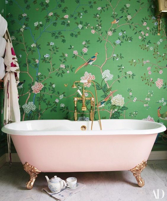 Amazing green printed floral wallpaper and a pink clawfoot bathtub that matches the wallpaper for a delicate look.