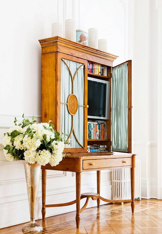 A refined vintage secretary style desk with a TV and books is a lovely idea to hide your TV with much elegance.
