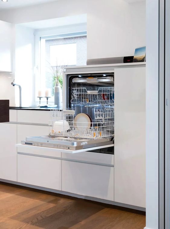 A sleek minimalist white kitchen with a dishwasher hidden inside one of the cabinets to keep the look ultra-minimal.