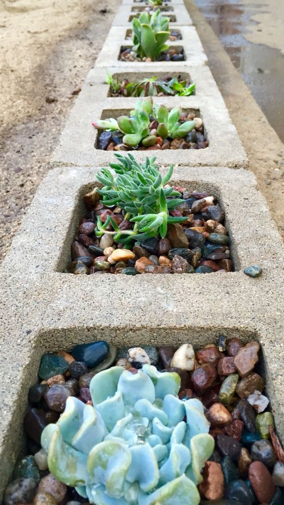 Sunken cinder blocks used as planters for succulents and pebbles is a bold modern idea.