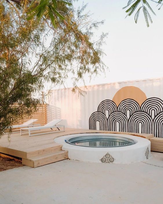 A boho deck with loungers, a stock tank pool and some wall decor is laconic and very chic.