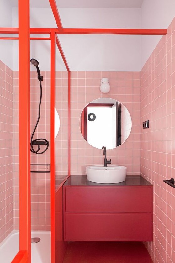 A bright modern bathroom with pink tile walls, a fuchsia floating vanity and orange frames is extra bold.