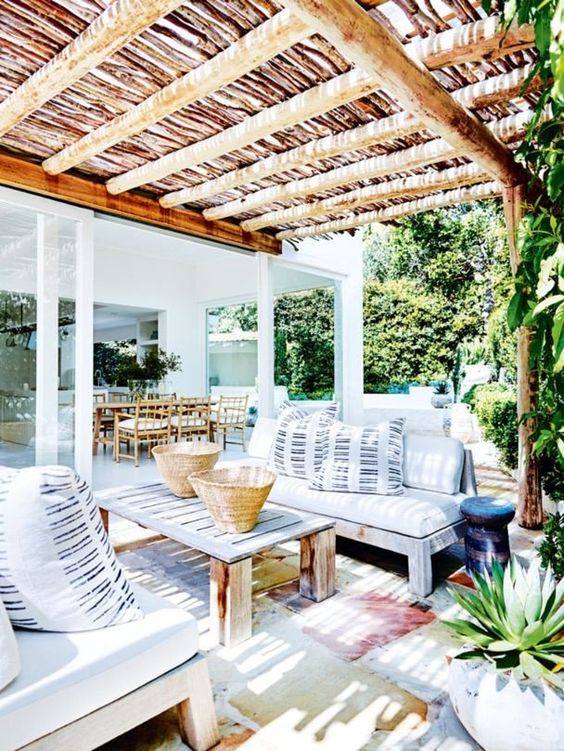 A bright summer terrace with wooden furniture, watercolor rugs and striped pillows feels very island-like.