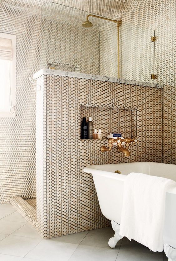 A chic bathroom with grey tiles and penny ones on the walls, a pony wall, brass touches and a vintage bathtub.