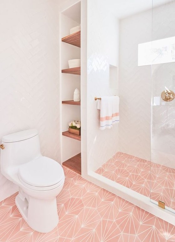 A chic contemporary bathroom with pink printed tiles on the floor, gold touches and fixtures plus simple white tiles on the walls.