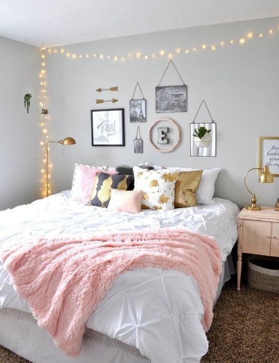 Grey walls provide a calm backdrop in this chic teen girl bedroom, highlighting the large bed adorned with printed pillows. A lovely gallery wall adds personal flair, while lights over the bed create a cozy and inviting atmosphere.