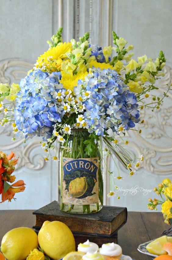 A clear jar with bright yellow and blue flowers is a bold and cool summer centerpiece with a vintage feel.