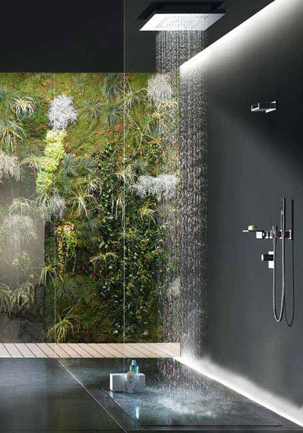 A contemporary bathroom with a glazed wall and a view of an outdoor living wall, black stone tiles and a rain shower head.