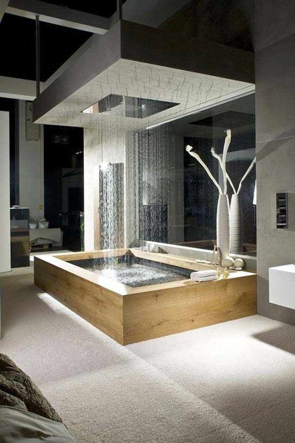 A contemporary bathroom with a rectangular-shaped bathtub and a large rain shower over it plus built-in lights.