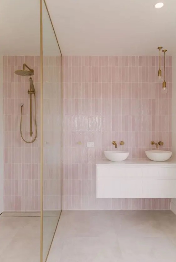 Pink skinny tiles and neutral large scale tiles highlight this modern bathroom. Brass fixtures and a white floating vanity enhance the decor. The overall design is both stylish and welcoming.