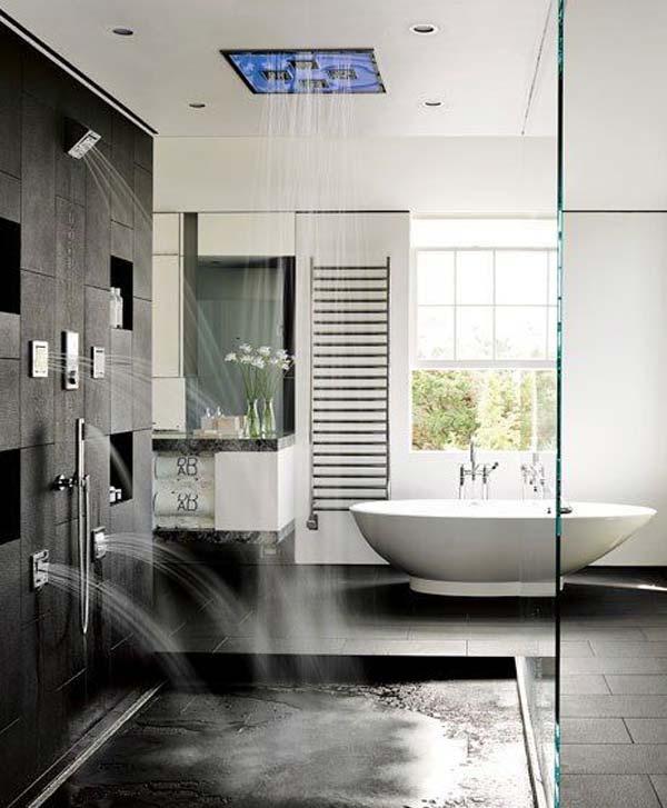 A contemporary black and white bathroom with black stone tiles, an oval tub and rain shower heads on the wall and ceiling.