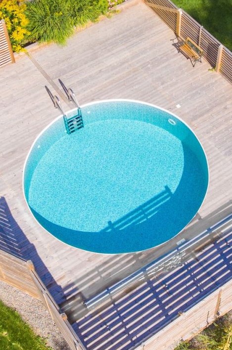 A contemporary wooden deck with a bench and a large round pool that invites you in looks amazing.