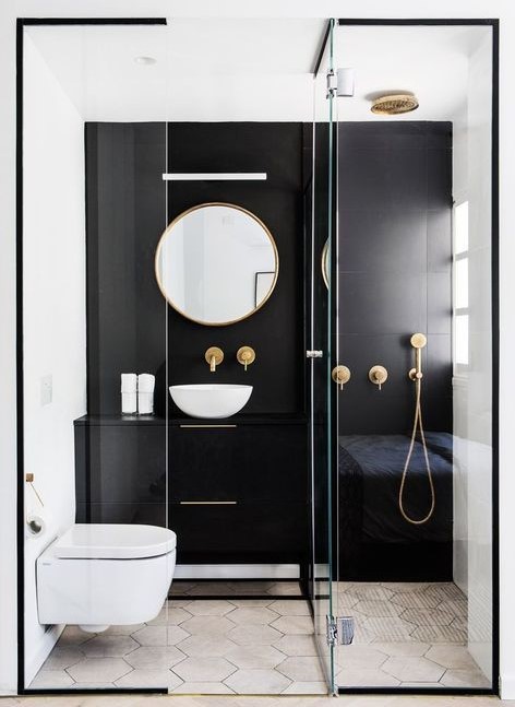 A contrasting small bathroom with a black statement wall and vanity, a shower, a round mirror and a bowl.