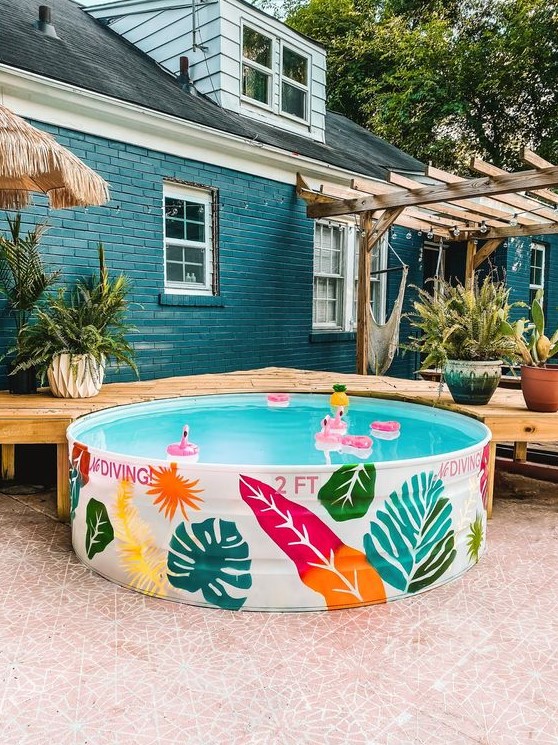 A cool stock tank pool with colorful painted elements for decor and colorful floats is a lovely idea to have in your summer backyard.