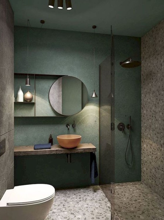 A creative small bathroom with a green wall, terrazzo flooring and wall, a wooden floating vanity and a coral bowl sink.
