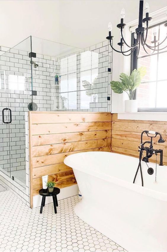 A farmhouse bathroom clad with hex and subway tiles, a pony wall clad with wood and a lovely vintage chandelier.