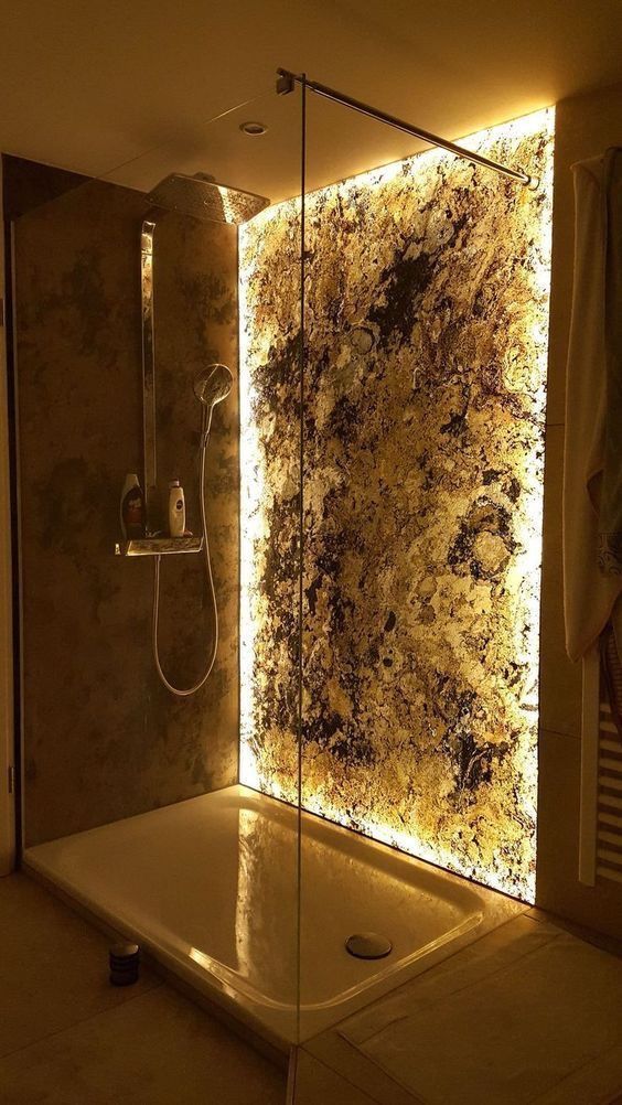 A gorgeous shower space with a lit up stone accent wall and modern fixtures plus a rain shower - this accent wall just wows.