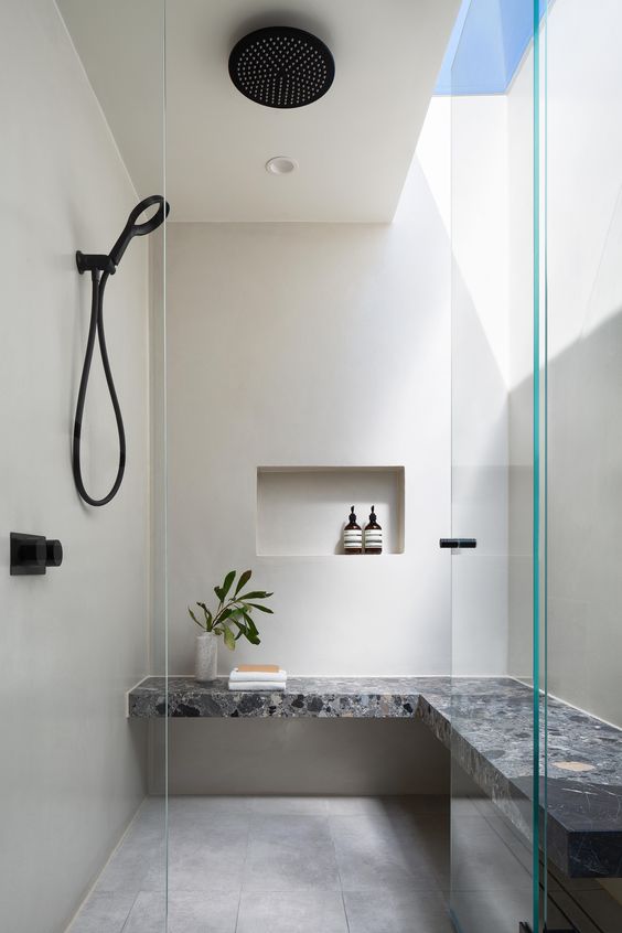 A laconic contemporary shower space with natural light and a catchy built-in stone bench plus a rain shower is amazing.
