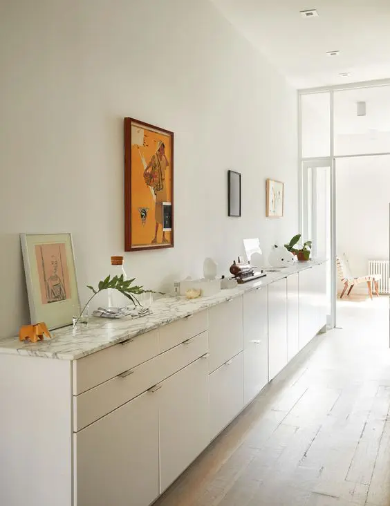 A large white console table with a marble countertop composed of IKEA Metod cabinets, with decor and artwork is adorable.