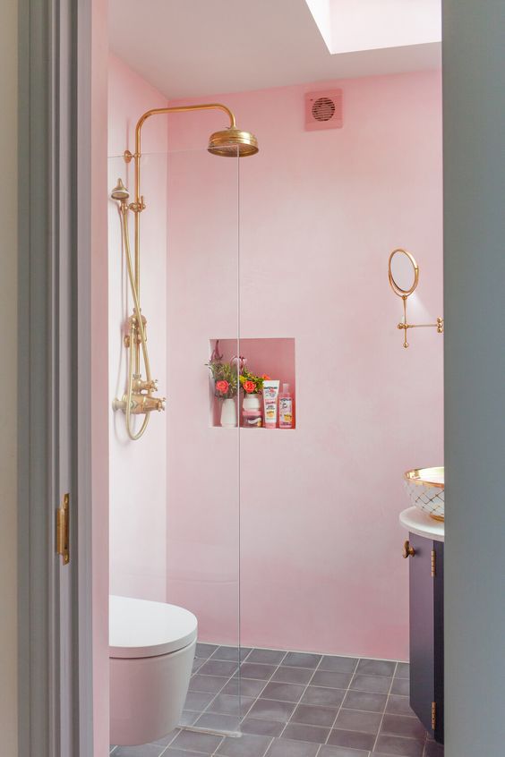 A light pink bathroom with a rounded vanity, a niche shelf, some gold fixtures is a pretty and fun idea, and a skylight adds natural light.