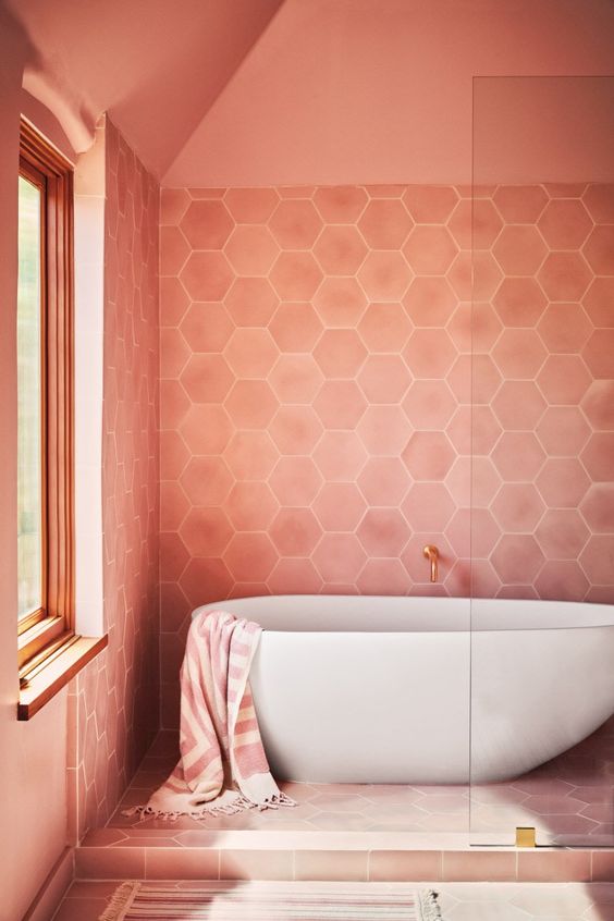 A light pink bathroom with hex tiles, an oval tub, a shower space is a warm and welcoming space.