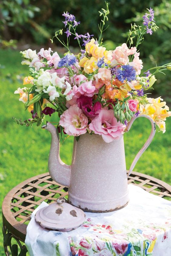 A light pink teapot with a colorful floral arrangement is a bright and cool decoration with a vintage feel.