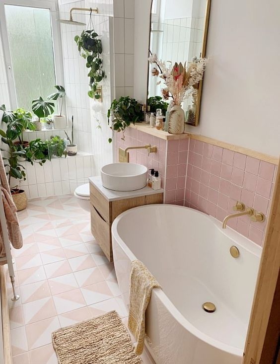 A modern bathroom clad with pink and pink geo tiles, a shower space with potted plants, a vanity with a sink and an oval tub.