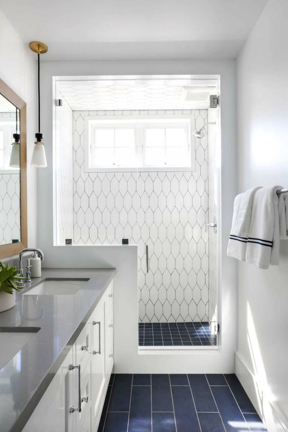 A modern coastal bathroom clad with navy and white tiles, a pony wall in the shower space and a white vanity.