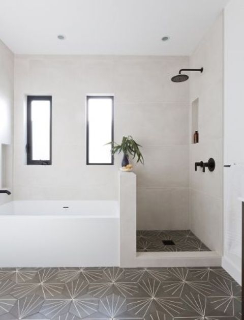 A neutral bathroom with mosaic tiles on the floor and neutral ones on the walls, a shower space with a pony wall that separates a shower and a bathtub.