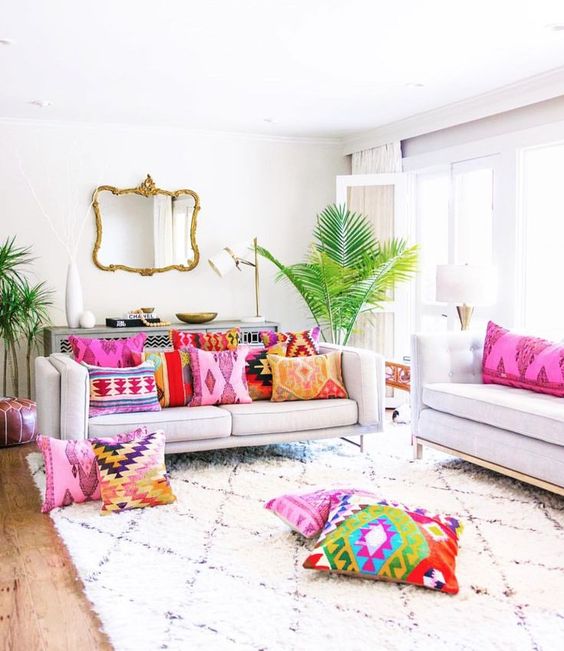 A neutral living room infused with bold printed pillows and tropical plants in pots for a summer feel.