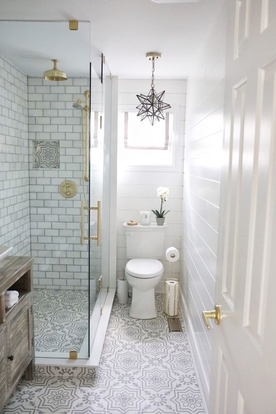 A neutral small bathroom with beadboard, printed tiles, subway tiles in the shower, gold touches and a star-shaped chandelier.