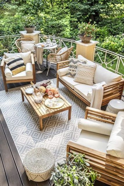A neutral summer terrace with wooden furniture, potted plants, rattan chairs and lots of cool textiles.