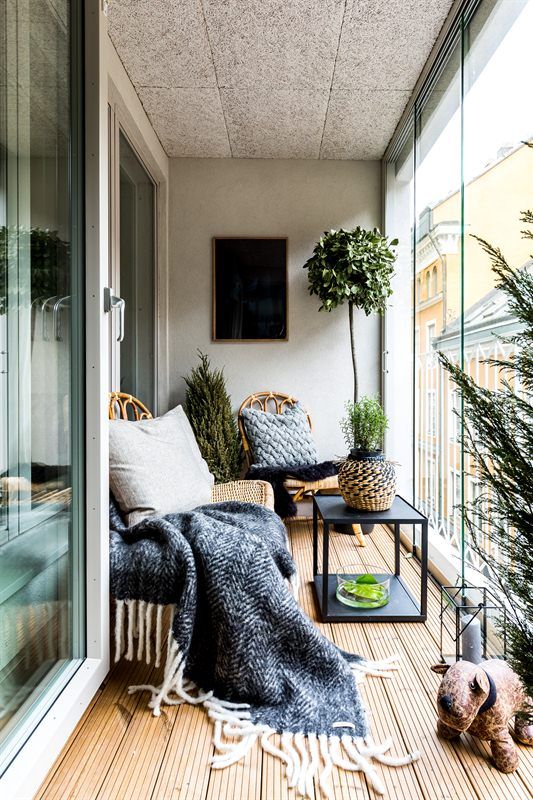 A Nordic balcony with rattan furniture, printed textiles, potted plants and candle lanterns for a chic space.