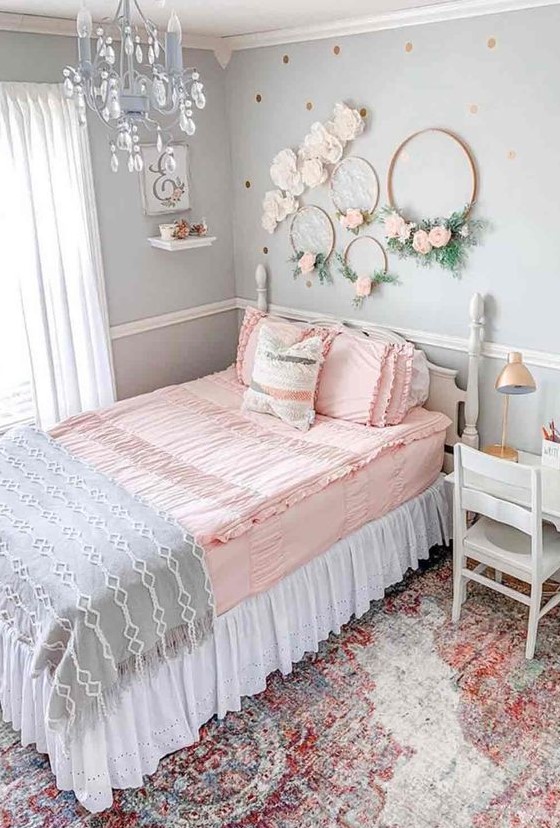 A romantic vintage teen bedroom with light blue walls, vintage neutral furniture, wreaths with blooms, a blue crystal chandelier and pastel bedding.