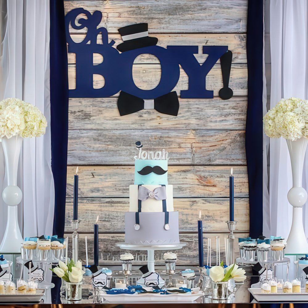 a rustic boy's baby shower dessert table with navy candles, white floral arrangements, letters on the backdrop and sweets.