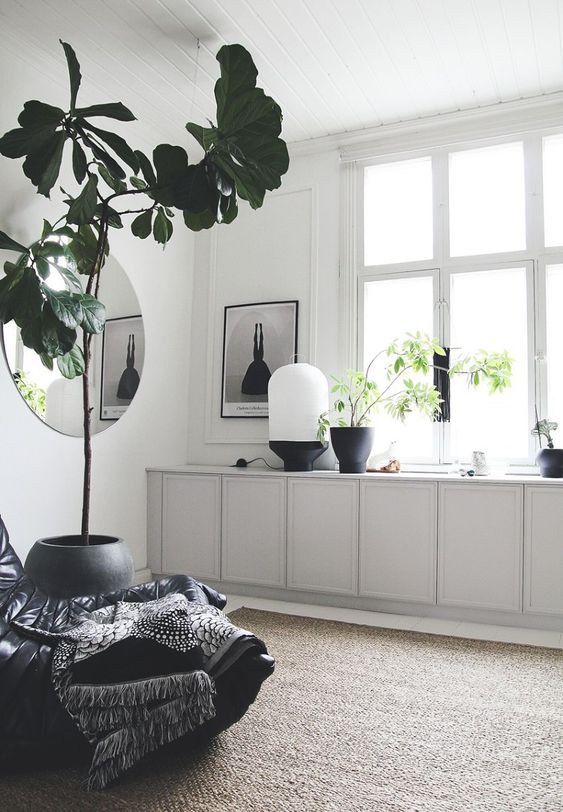 A Scandinavian space with light greey IKEA Metod cabinets, some lovely decor, a potted tree and a black chair.