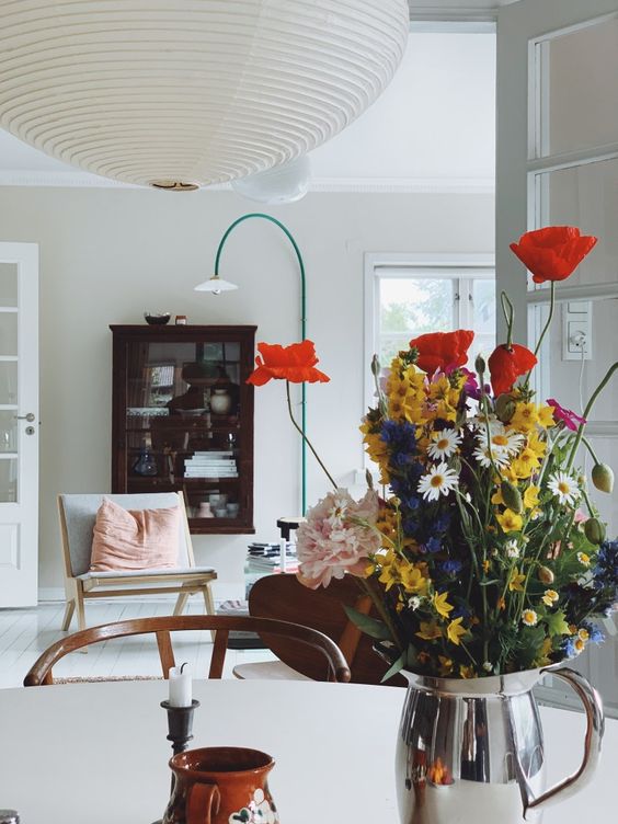 A silver milkpot with colorful blooms is a bright and fun decoration or centerpiece with a relaxed feel.