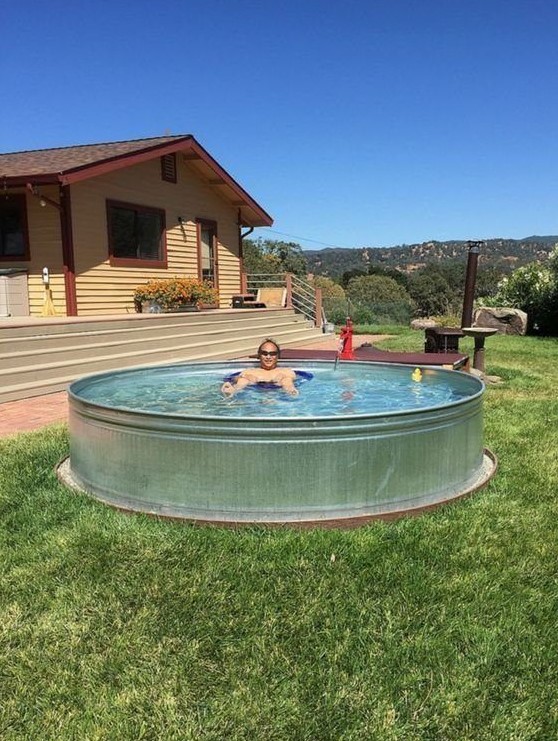 A simple stock tank pool placed on the grass is a perfect solution for a hot and sunny summer day to chill in your backyard.